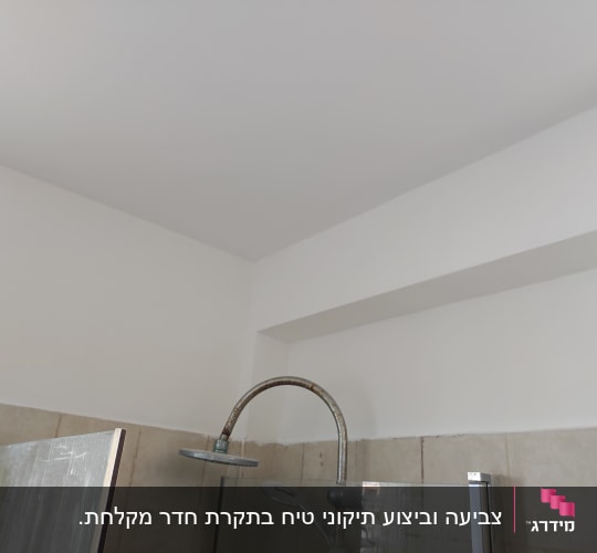 קיר ותקרה צבועים בלבן בחדר אמבטיה